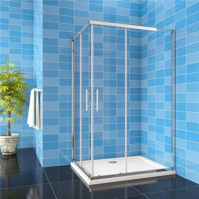 A modern bathroom with blue tiled walls, a black tiled floor, a potted plant, and a glass shower enclosure.