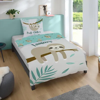 A child's bed with sloth-themed bedding, set in a bedroom with natural light from a large window.