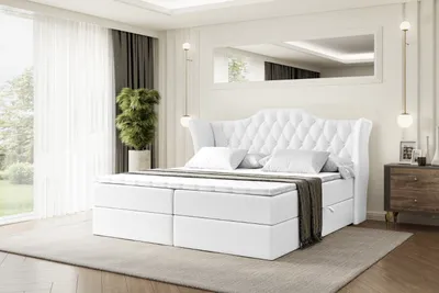 A white upholstered bed with a tufted headboard is shown in a bedroom setting.