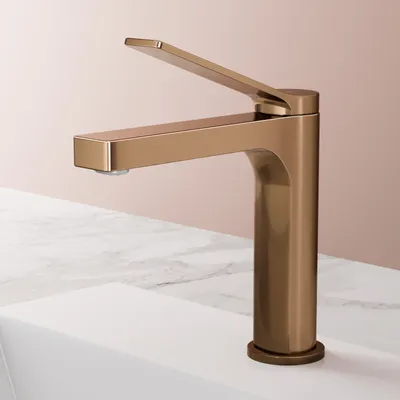 A rose gold faucet is shown on a white sink with a marble countertop.