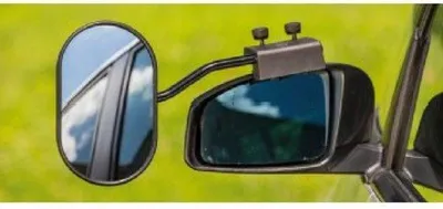 A close-up view of a caravan mirror attached to a vehicle's side mirror, set against a blurred green background.