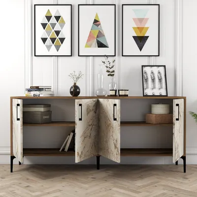 A sideboard with decorative items and artwork displayed above it, set against a white paneled wall.