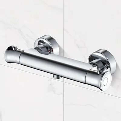 A chrome shower thermostat valve mounted on a tiled wall.