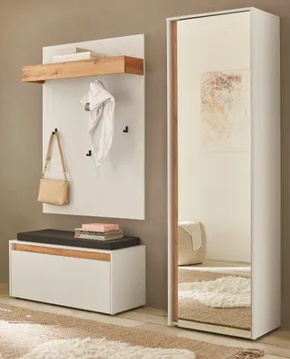 A modern entryway with a white and wood tone coat rack, bench, and mirror.