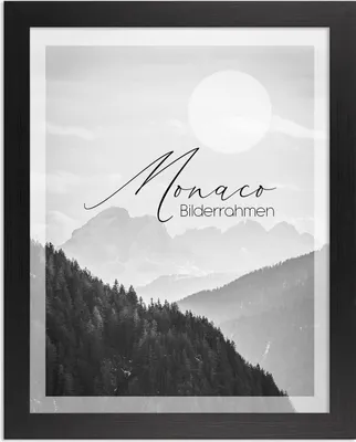 A framed black and white landscape photograph of mountains and trees, with a sun-like circle in the sky.