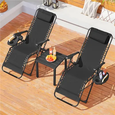 Two black zero gravity chairs with a small table between them on a wooden deck.