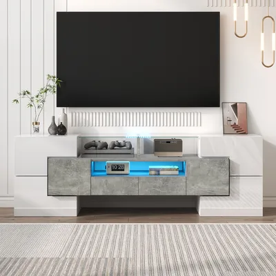 A modern TV stand with a large black television mounted above it, in a well-lit room with a striped rug on the floor.
