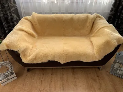 A sheepskin rug draped over a sofa in a room.