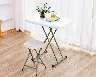 A small white folding table and stool set up indoors, with sheer curtains in the background.