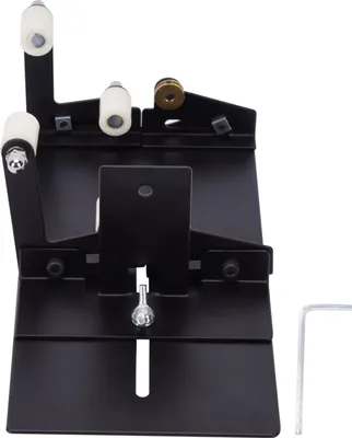 A black metal bottle cutter attachment with white and gold rollers, shown against a white background. A hex wrench is visible on the right.
