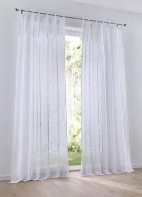 A white sheer curtain hanging in front of a window with greenery visible outside.