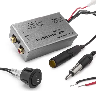 A close-up shot of an FM stereo modulator and its accessories on a white background.