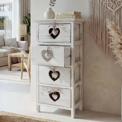 A white chest of drawers with heart cutouts in a room with a sofa and a macrame wall hanging.