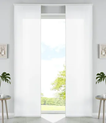 A pair of white panel curtains are drawn open, revealing a view of trees and sky through a window.