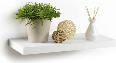 A white floating shelf with decorative items on it.
