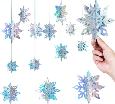 A hand holding a holographic snowflake decoration, with other similar decorations hanging in the background.