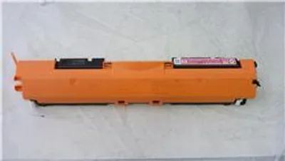 A single toner cartridge is shown lying horizontally on a light gray surface.