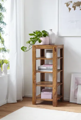 A wooden shelf unit with decorative items and books in a room with a window and curtains.