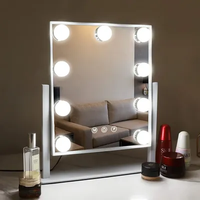 A vanity mirror with lights is displayed on a surface, with some cosmetic products in the foreground.