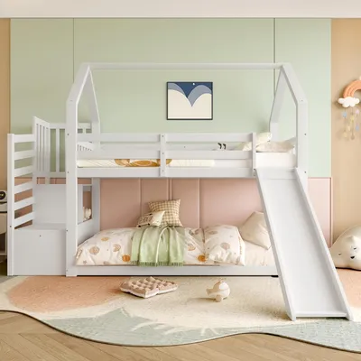 A child's bedroom with a white bunk bed featuring a slide and stairs, decorated with colorful bedding and wall art.