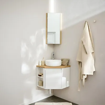 A modern bathroom corner with a vanity, sink, faucet, and a robe hanging on the wall.