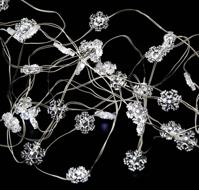 A close-up shot of a string of snowflake-shaped LED lights against a black background.