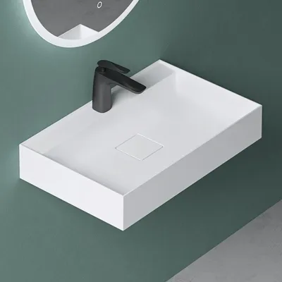 A modern white rectangular sink with a black faucet is mounted on a teal wall.