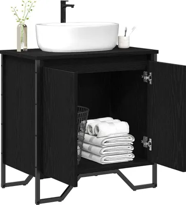 A black vanity cabinet with a white sink on top and its doors open, revealing towels and a basket inside.