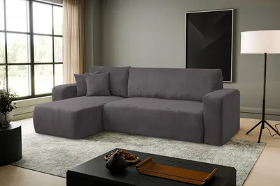 A dark gray sectional sofa is shown in a well-lit living room with large windows.