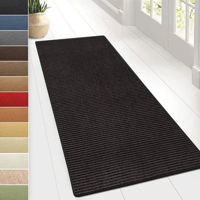 A dark-colored, striped rug is laid out on a white wooden floor, with a glimpse of a doorway and windows in the background. To the left, a vertical strip displays swatches of various rug colors.
