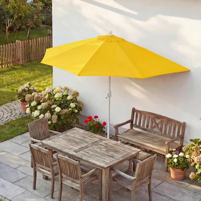 An outdoor patio scene with a table, chairs, bench, and a yellow umbrella.