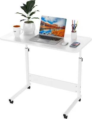 A white rolling laptop table with a laptop, plant, mug, and pens on it.