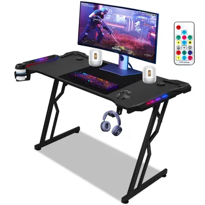 A black gaming desk with a monitor, keyboard, mouse, headphones, and a cup holder.