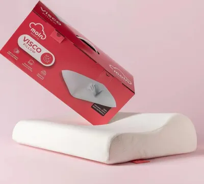 A pillow is shown next to its packaging, which is tilted and angled.