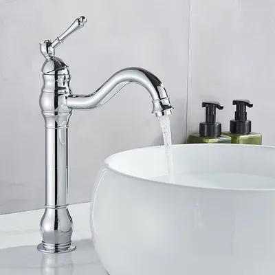 A chrome faucet is running water into a white basin, with two soap dispensers in the background.