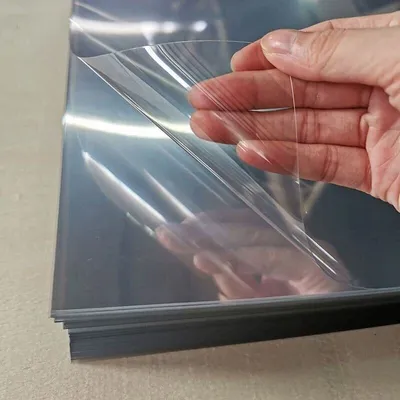 A hand is peeling a protective film off a stack of clear sheets.