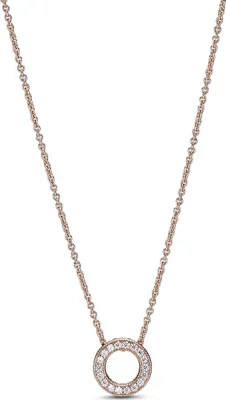 A close-up studio shot of a rose gold necklace with a circular pendant encrusted with small white stones, set against a plain white background.