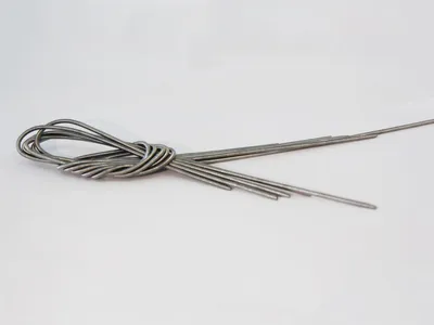 A bundle of metal wires tied together with a knot, lying on a white background.