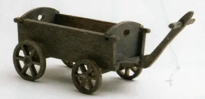 Ein kleiner, hölzerner Kastenwagen. Er ist dunkelbraun, aus fein bearbeitetem Holz gefertigt.
