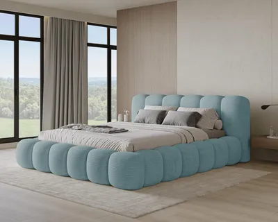 A modern bedroom with a large, plush blue bed as the centerpiece, featuring large windows with a view of greenery.