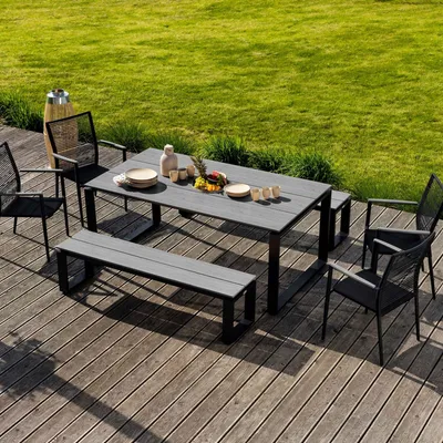 An outdoor dining set on a wooden deck with a grassy lawn in the background.