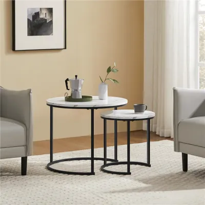 A living room scene with two nesting coffee tables, a chair, and a framed picture on the wall.