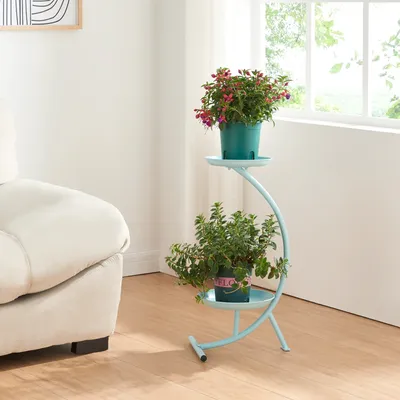 A light blue metal plant stand with two potted plants is placed next to a cream-colored sofa in a well-lit room with a window.