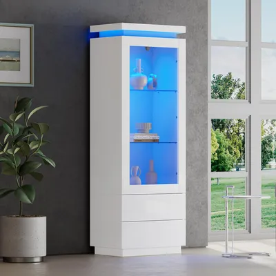 A white vitrine cabinet with blue LED lighting is displayed in a room with a gray wall and a large window. A potted plant is to the left of the cabinet.