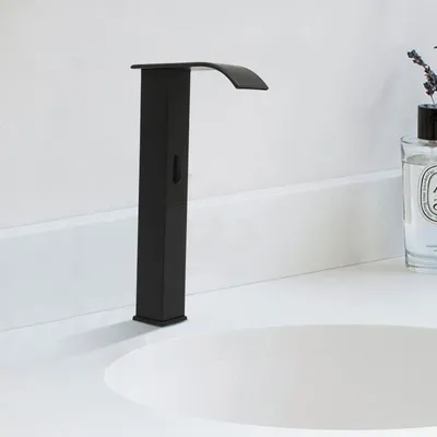 A black waterfall faucet is shown installed on a white countertop next to a sink. A bottle of perfume with lavender sprigs is visible in the background.