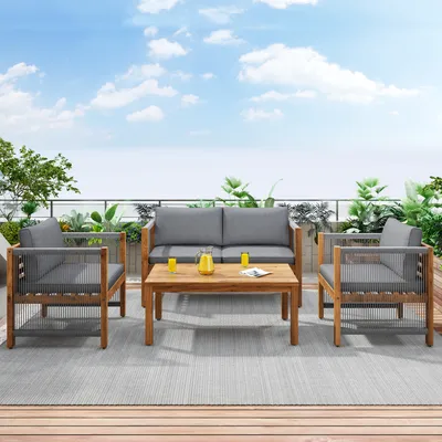 A patio furniture set on a deck with plants and a blue sky in the background.