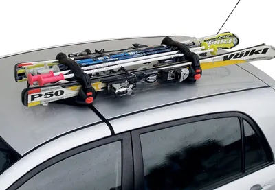 A ski rack with skis and poles mounted on the roof of a silver car.