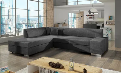 A modern living room with a large sectional sofa, a coffee table, and a view of a city skyline through large windows.