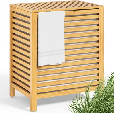 A wooden laundry basket with a towel hanging on the side, set against a white background with some green grass in the foreground.