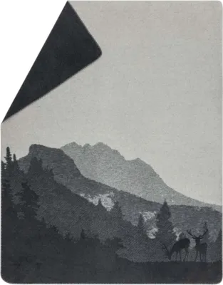 A blanket with a landscape design featuring mountains, trees, and deer.